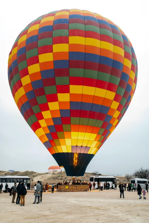 several people in the sand looking at two large  air balloons