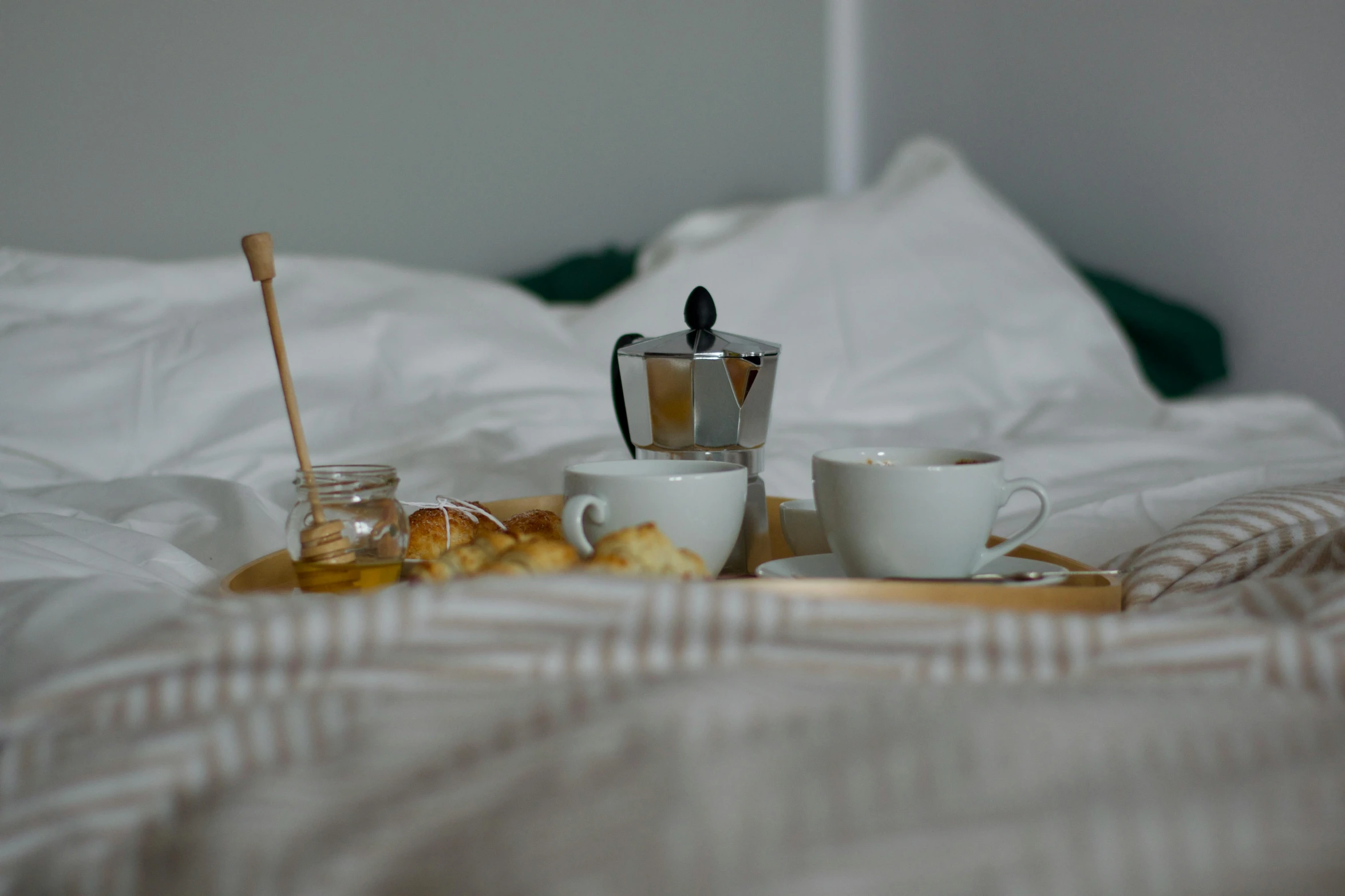 an unmade bed with cups on top of it