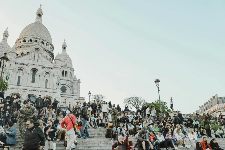 a crowd of people walking up stairs near a stone building