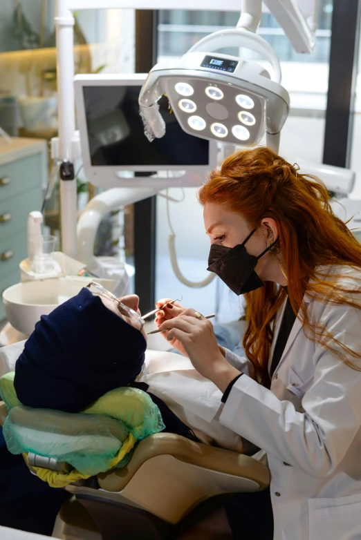 a girl in a dental gown in front of a woman in the dentist's chair