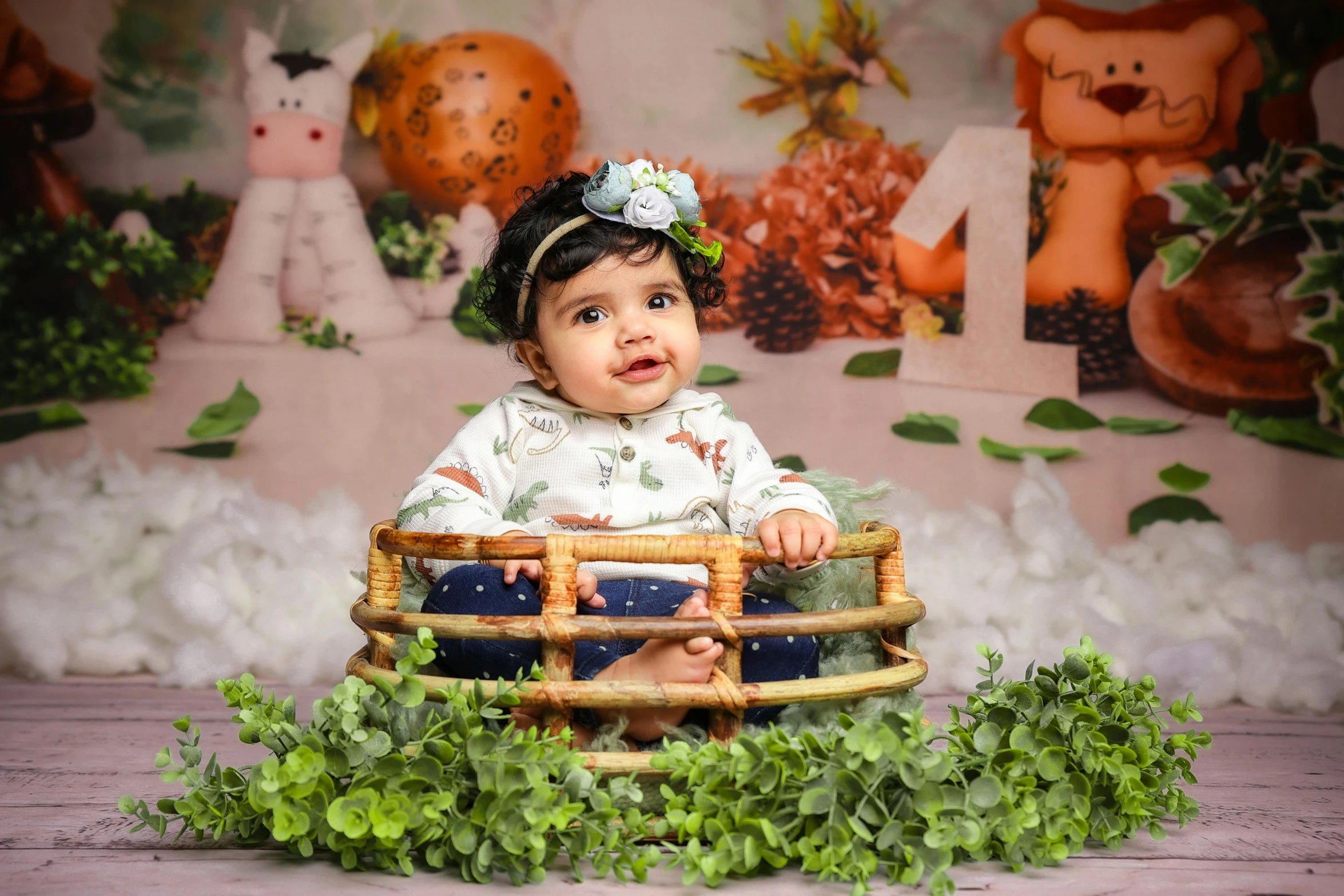 a baby is sitting on top of a basket with greenery