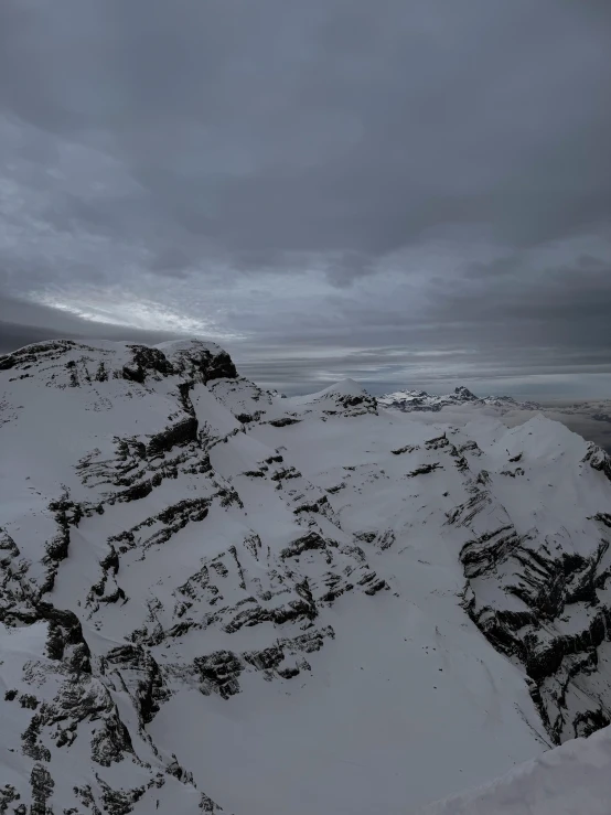 a snowy mountain is shown with dark clouds overhead