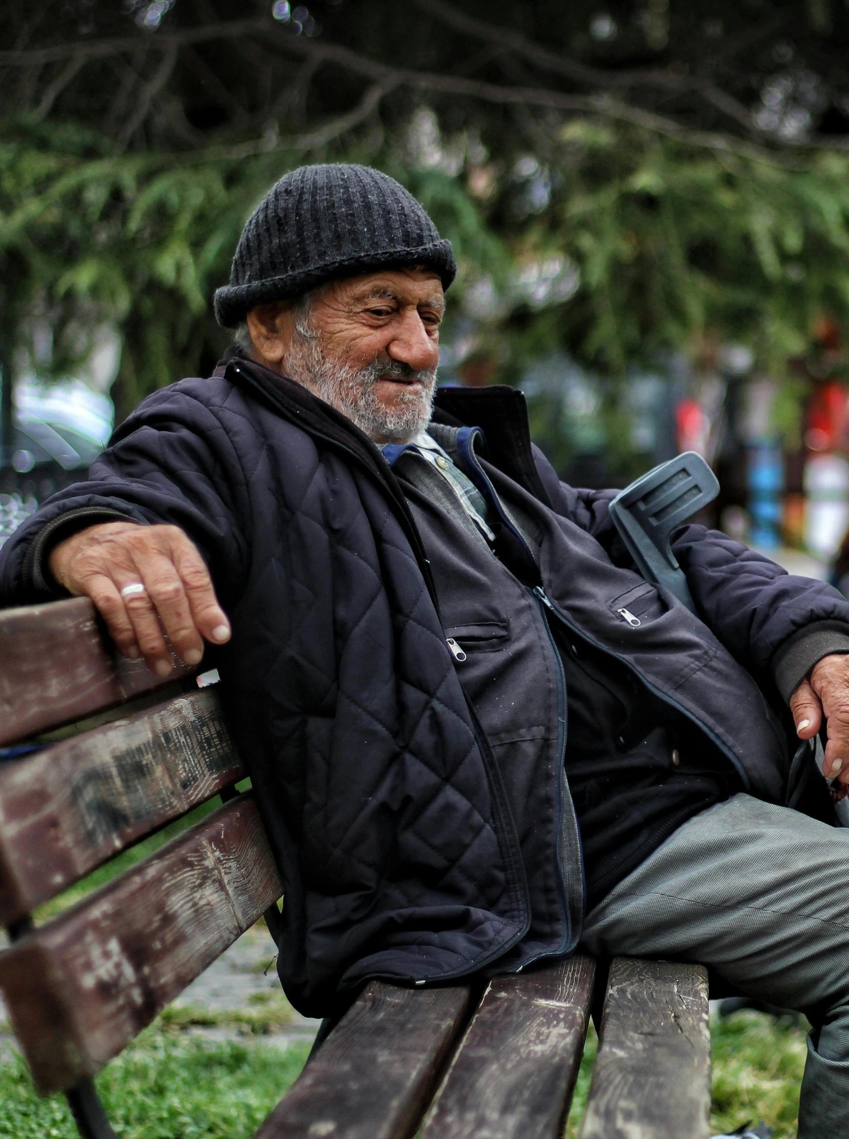 an old man sits on a bench on a windy day