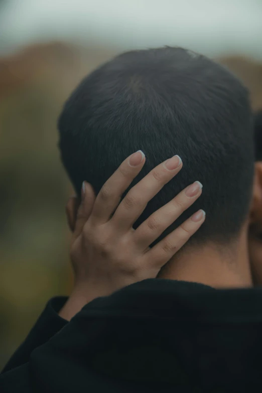 the back end of a person's head covered by their hands