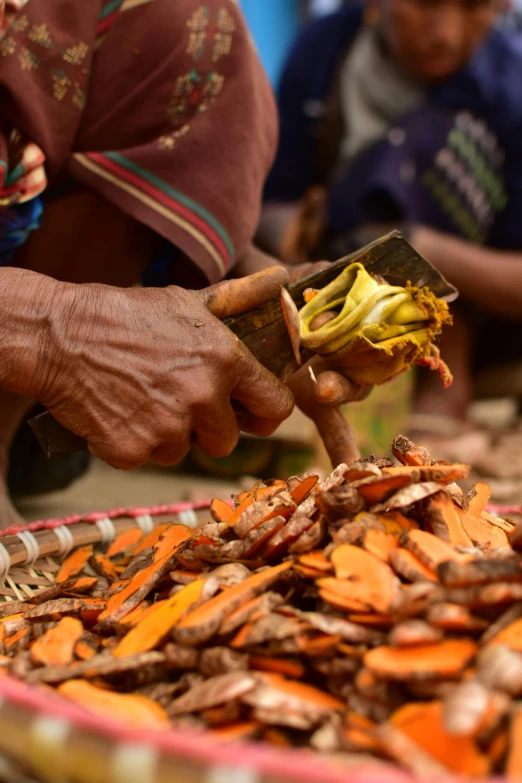 a man holding a knife in his hand over a pile of sliced bananas