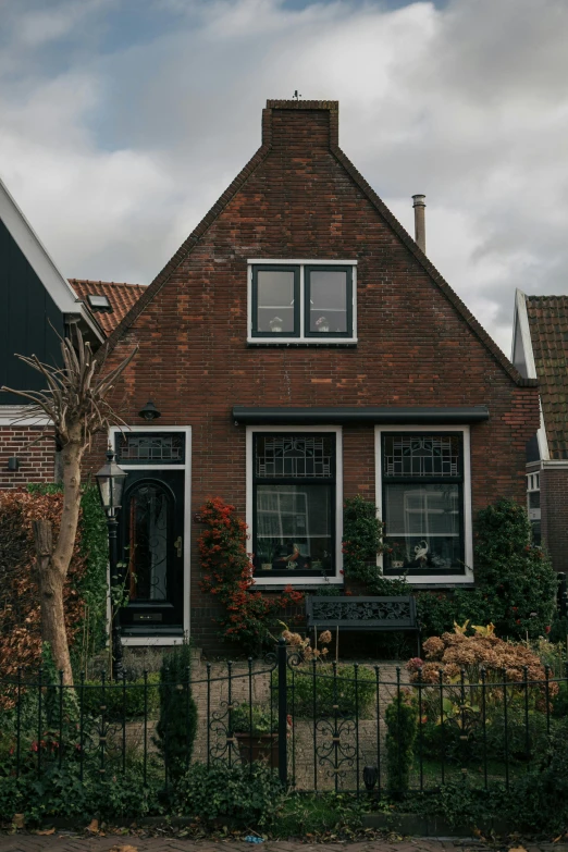 a brick building with two windows and some bushes