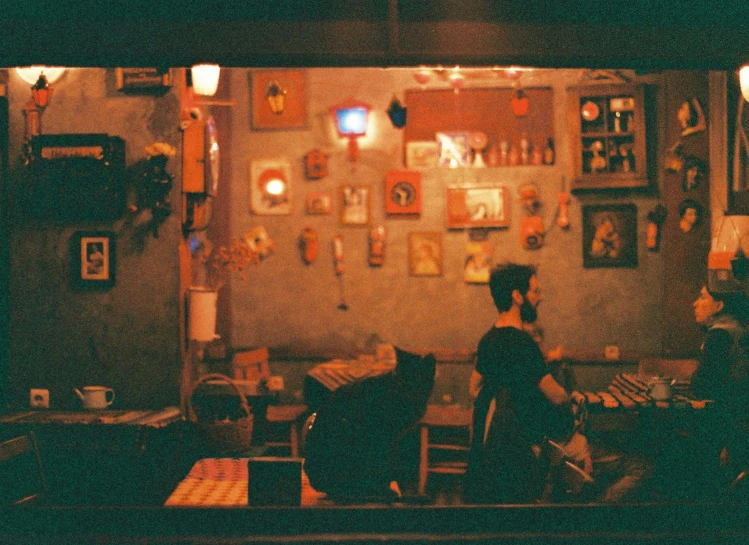 two women sitting at a table in an dimly lit room with various frames around them