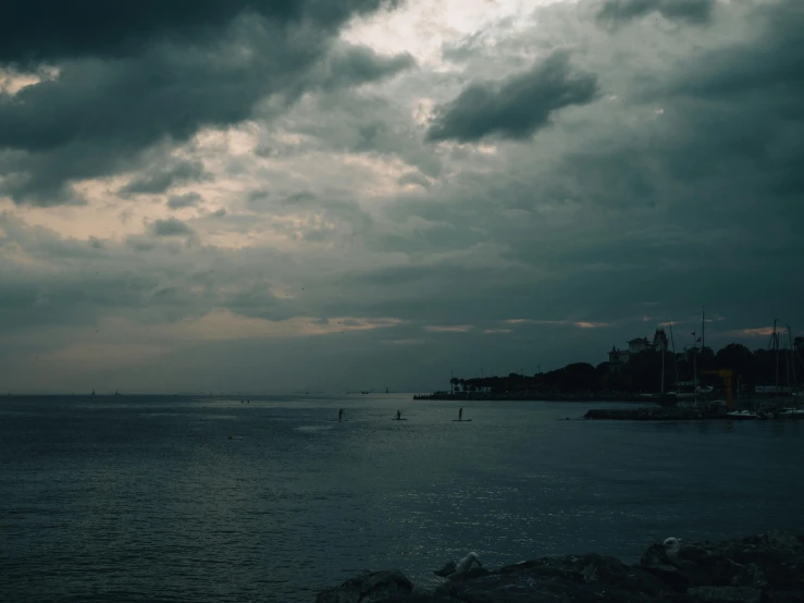 there is a lighthouse on the shore as dark clouds move across the water