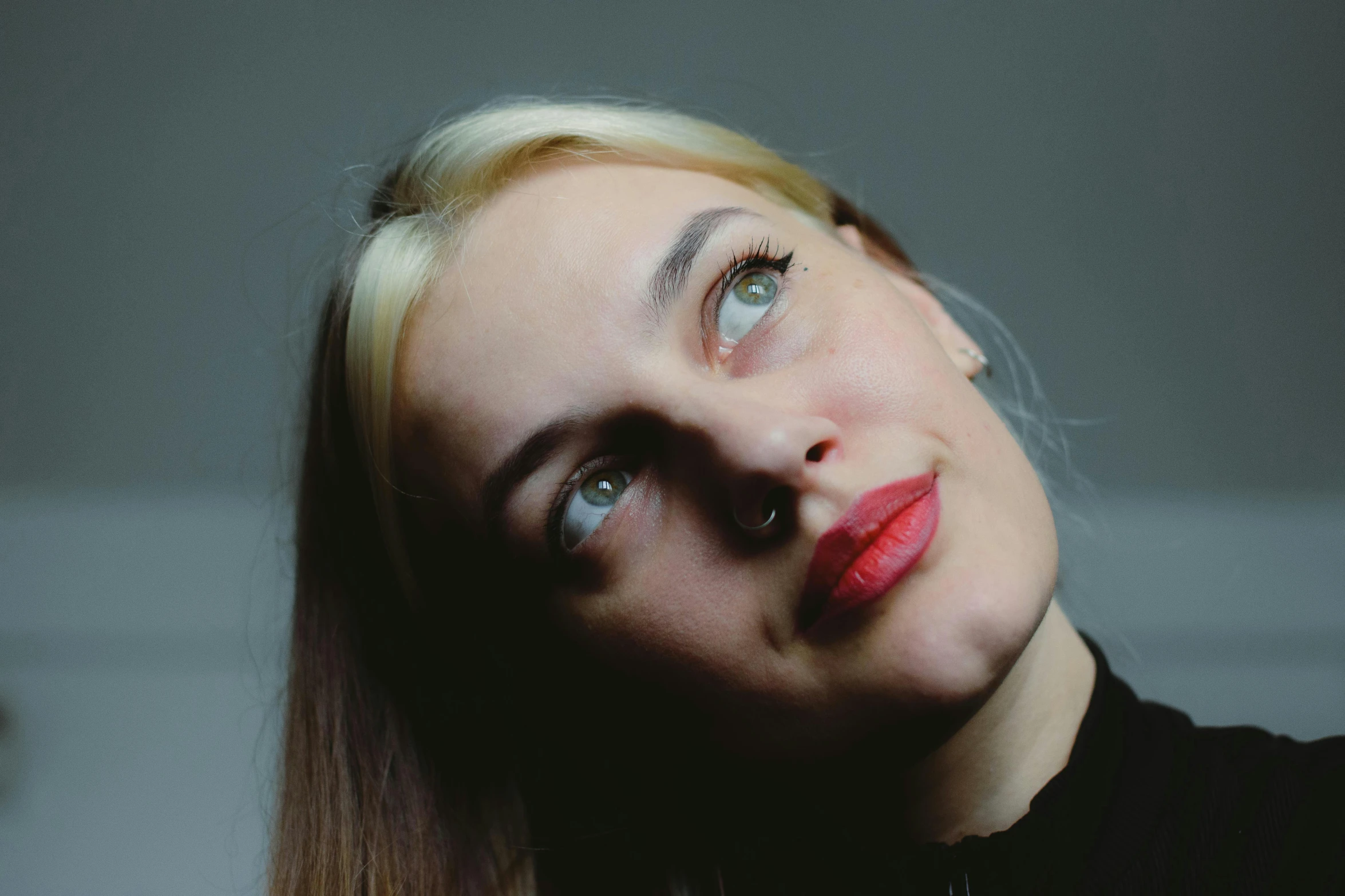 a blonde woman with long hair and red lipstick looks into the camera