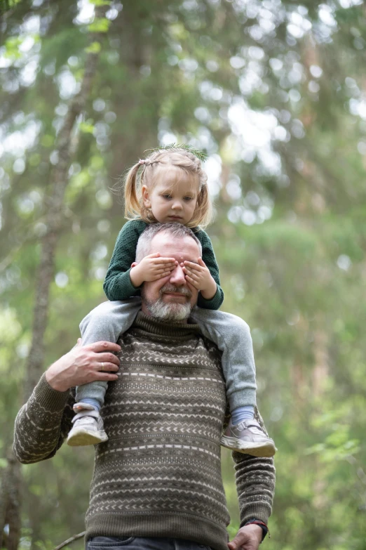 a man holding a child while they walk in the woods