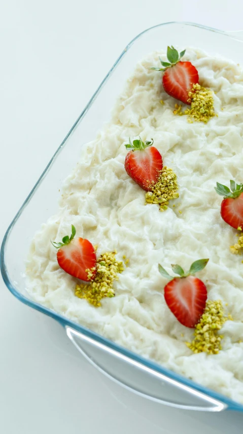 food in a glass dish covered with white whipped crumbs and fresh strawberries