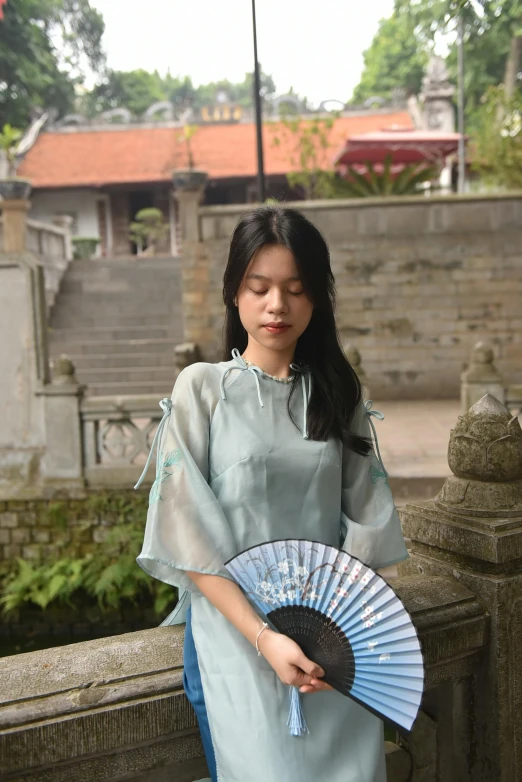 a woman is dressed in a blue traditional dress with a fan