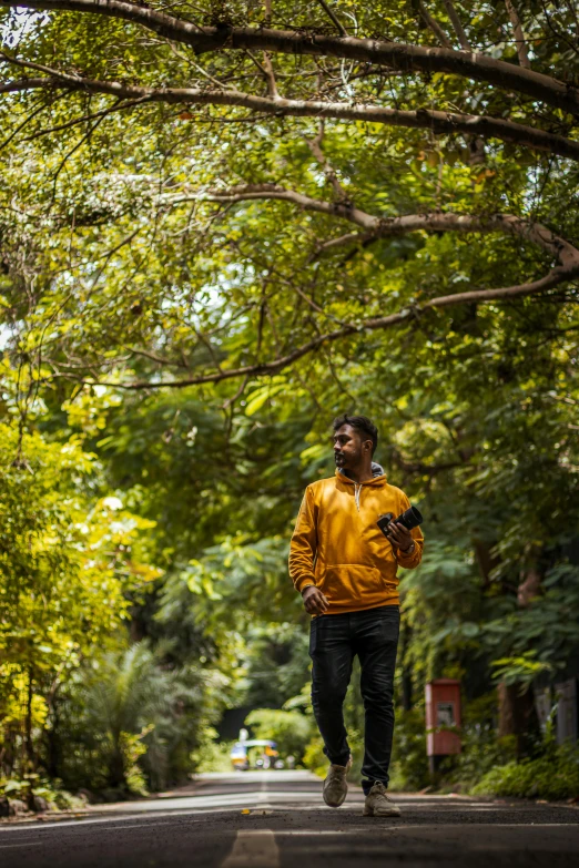 a man running down the middle of a street under trees