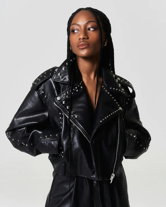 a model wears a black leather jacket and black pants with pearl trim