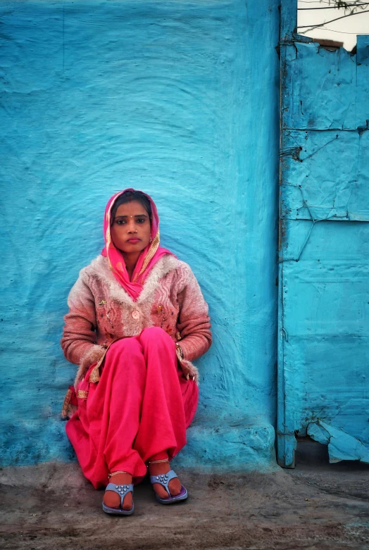 a woman sits in front of a blue wall