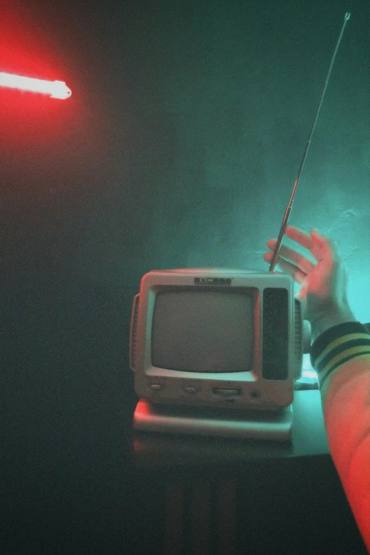 an old tv on a table being held up by a hand