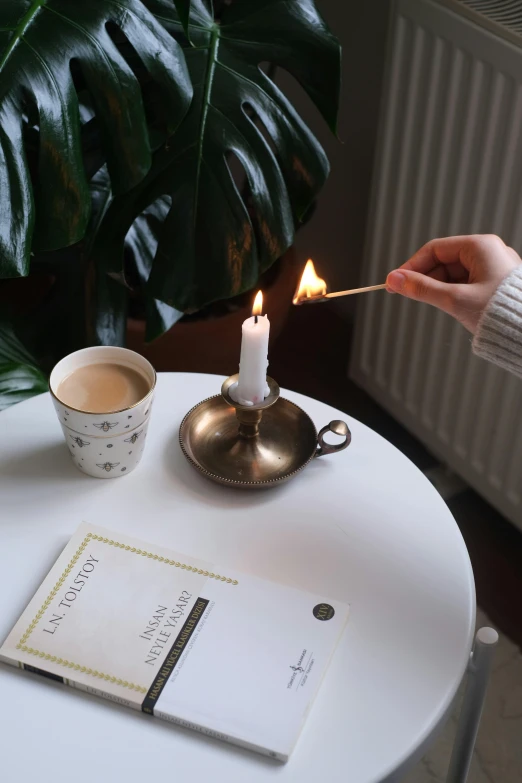 a candle on a saucer with an open note and book on it