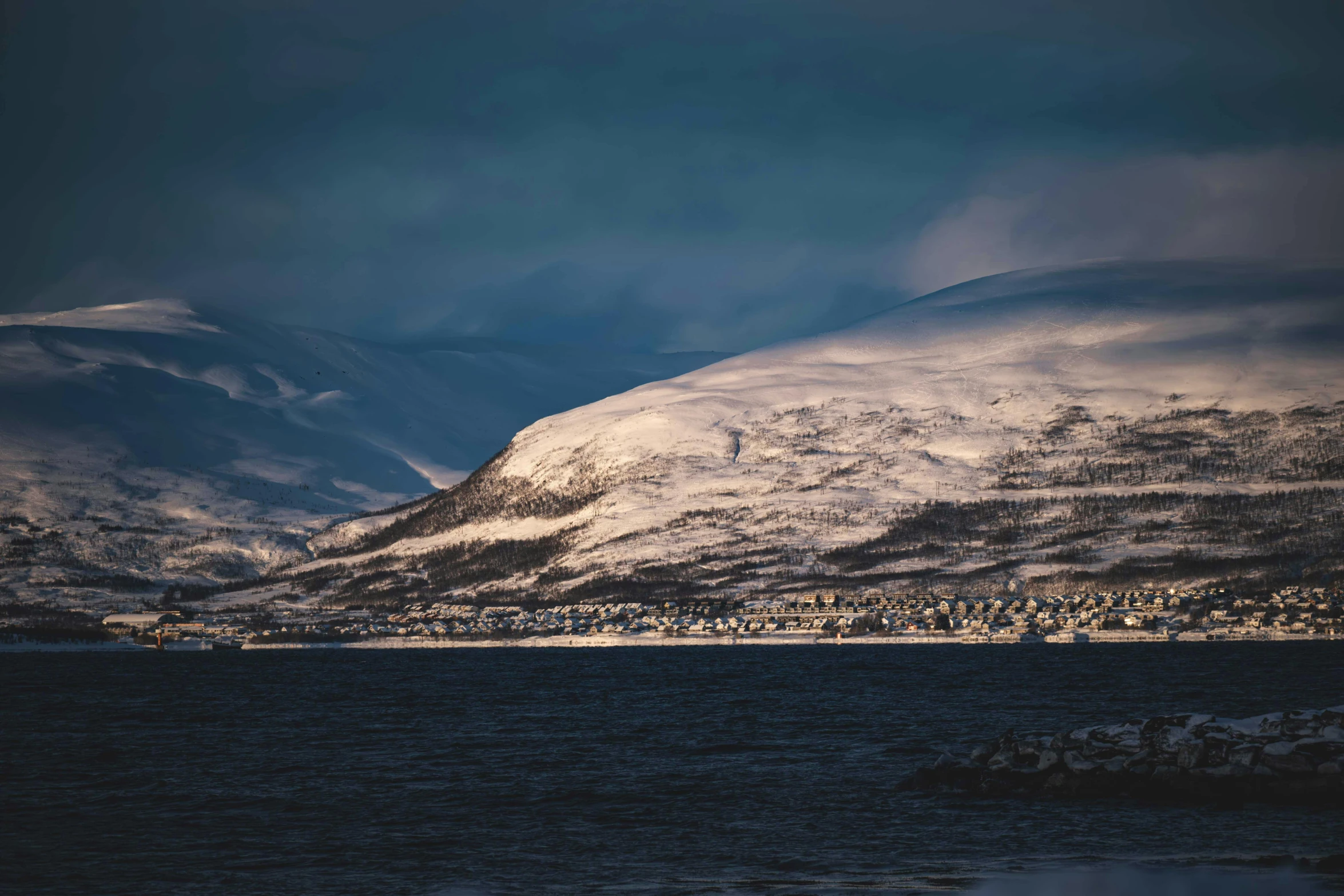 a beautiful snow covered mountain with a town nestled between them