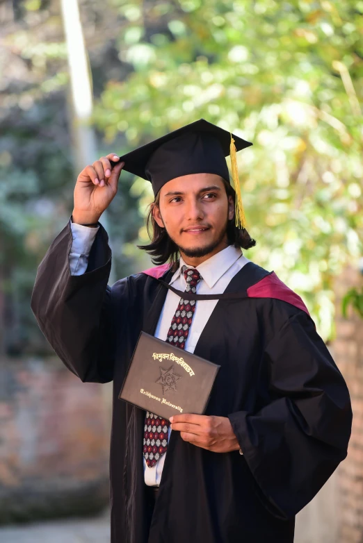 a man in a graduation gown poses with his hat on