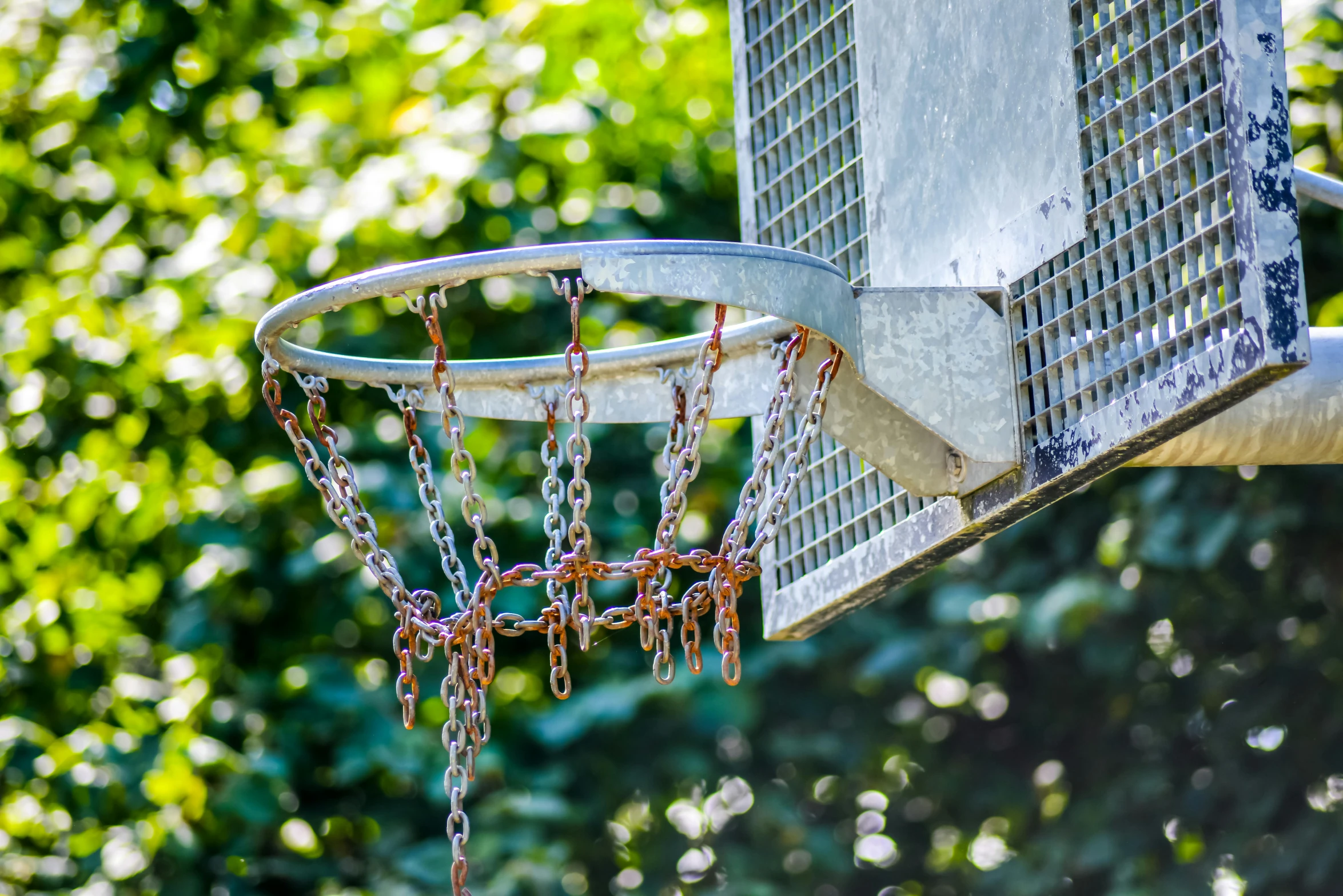 the net of an outside basketball court that has chains on it