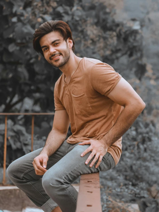 man posing for a portrait on top of a brick ledge