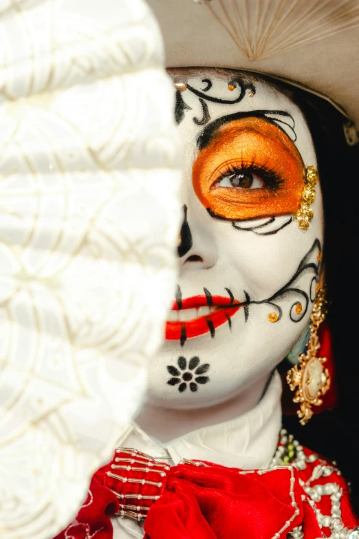 an intricately dressed woman with bright orange face paint