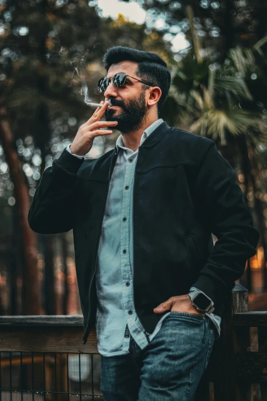 a bearded man in glasses smokes a cigarette