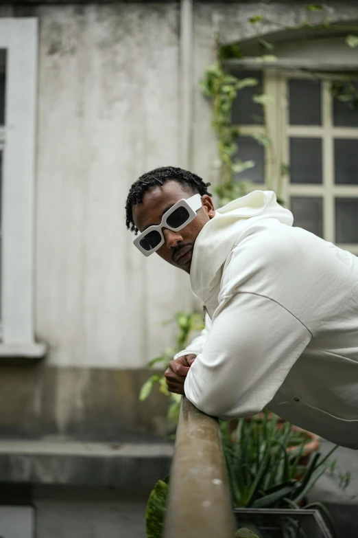 a man wearing sunglasses leaning on a wall