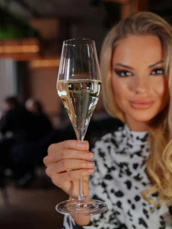 a pretty blond holding a glass of white wine