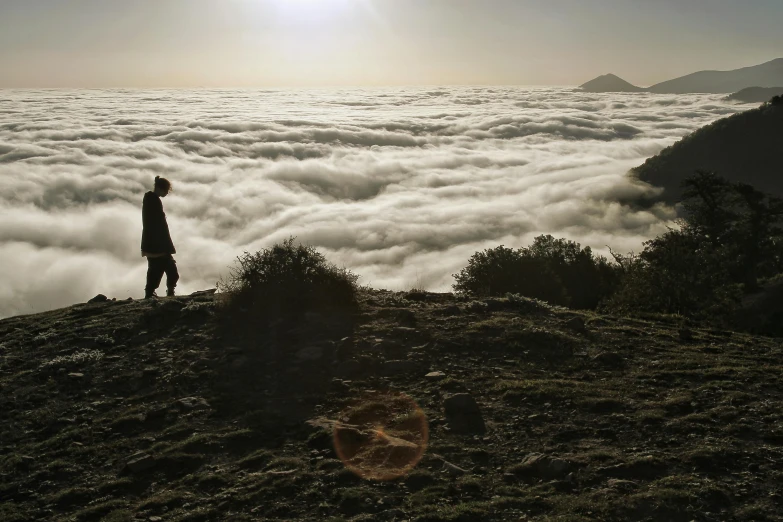 a man standing on top of a mountain above the clouds