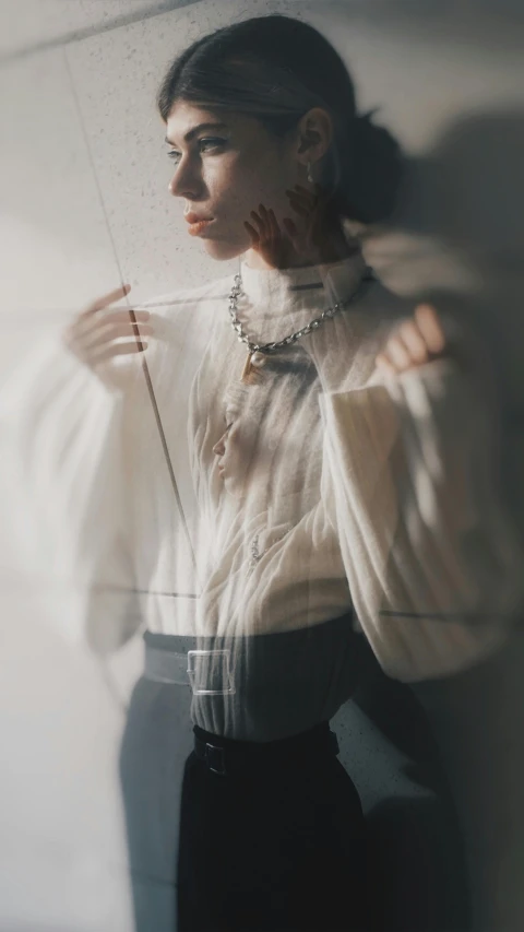 a woman standing next to a window, covering her face with a plastic bag