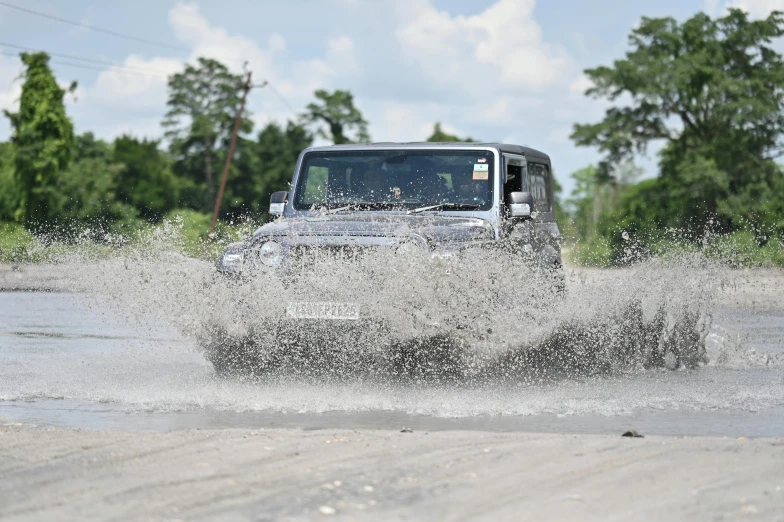 a jeep drives through water on a dirty road