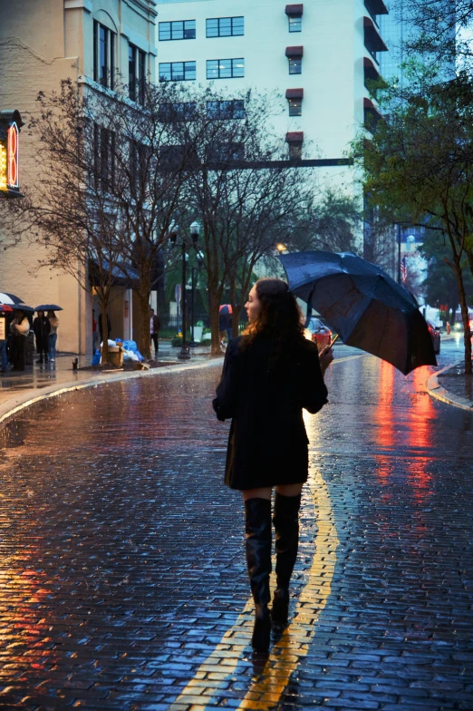 a woman is walking along a city street with an umbrella
