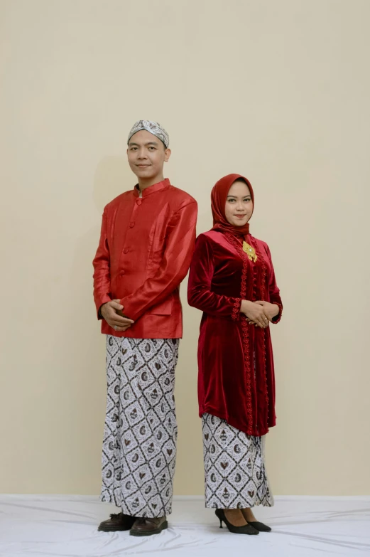 two people posing for the camera, while wearing ethnic clothing