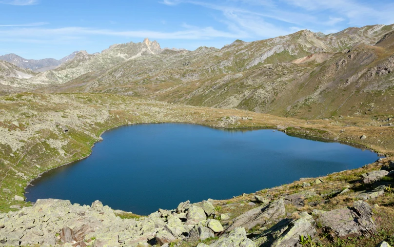 a large blue lake sits below a rocky mountain range