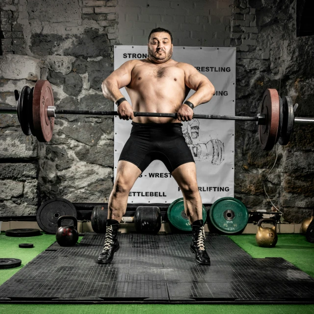 the weightlifter is standing above one shoulder on a gym mat