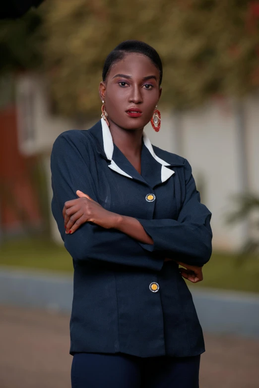 a woman wearing a blazer and posing with her arms crossed