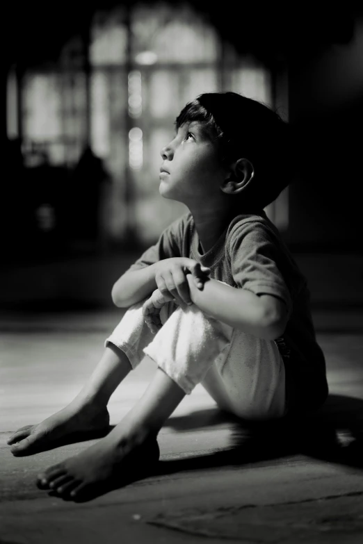 a boy is sitting on the ground while staring up