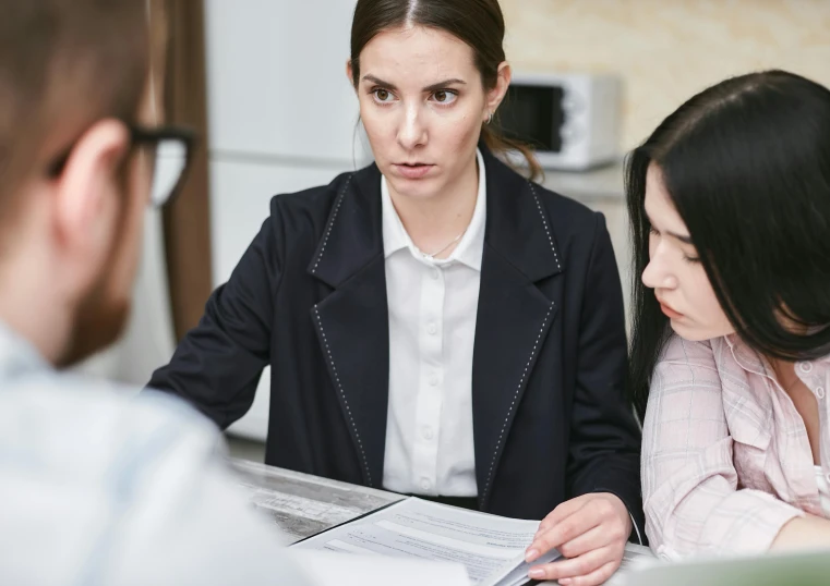 two women are discussing soing while one looks at her laptop