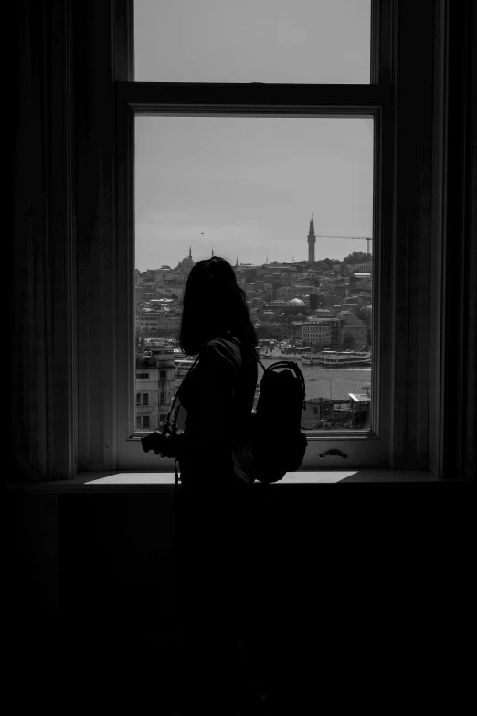 the silhouette of a person sitting in front of a window