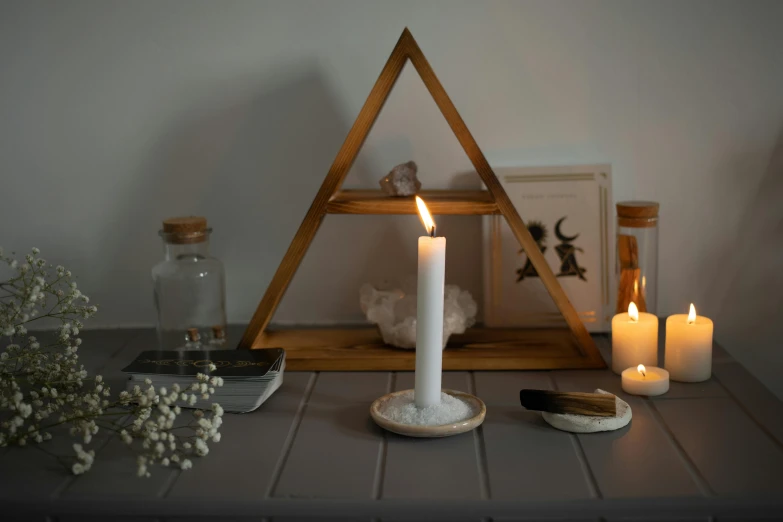 a candle in a wooden triangle surrounded by candles