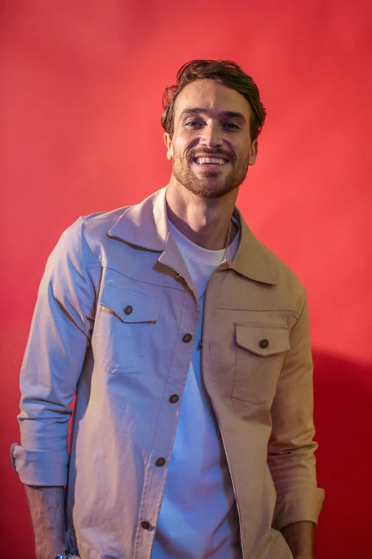 a man is standing and smiling while wearing a jacket