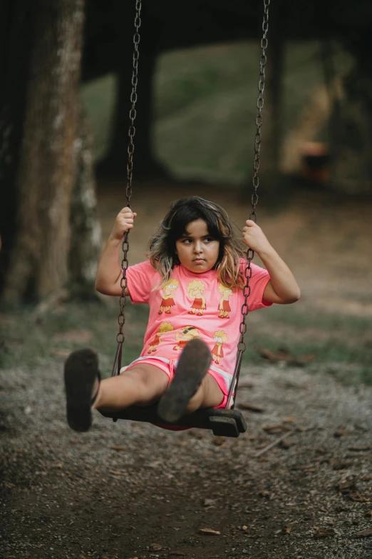 a little girl swings on a swing with her feet on the chains