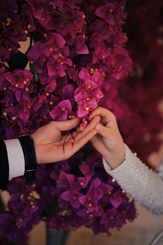 a bride holding her grooms hand as they take flowers