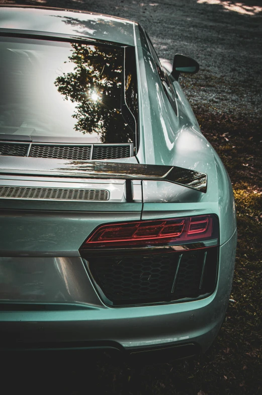 the rear of a shiny silver car sitting in grass