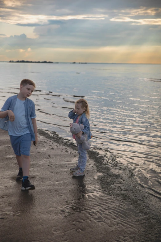 two children walk along the edge of a lake