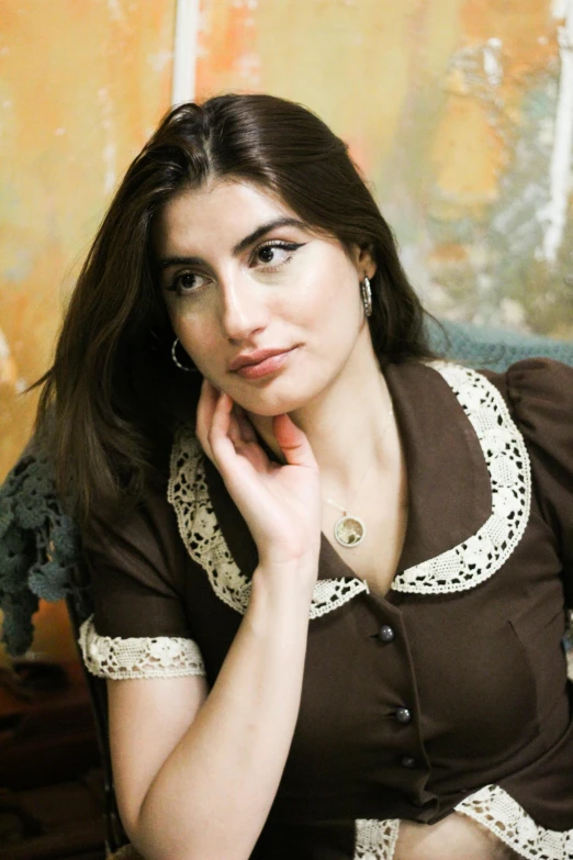 a beautiful young woman in brown and white shirt sitting