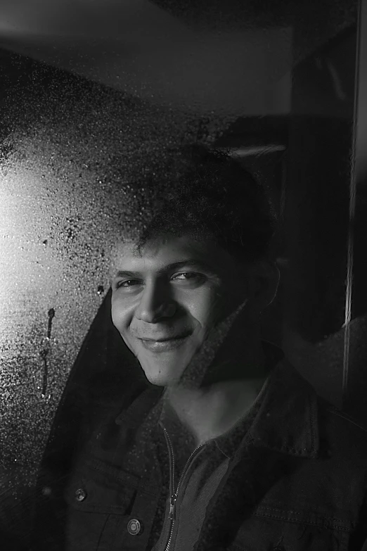 a man smiling next to an umbrella in the rain