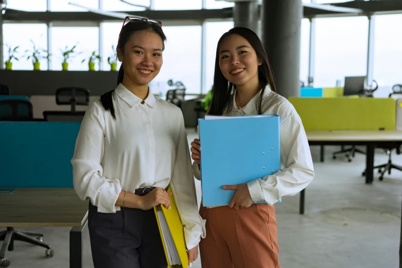 two women standing next to each other in an office area