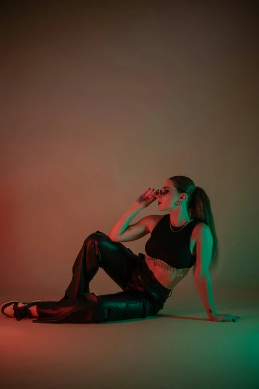 a woman posing in leather pants and boots, with her hand on her face